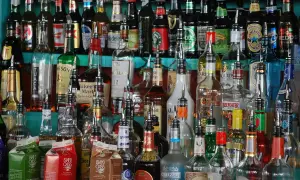 Różnorodne butelki alkoholi, w tym whisky, rum i wódka, gotowe do użycia. Zastanawiasz się, jak rozcieńczyć nalewkę? Tu znajdziesz inspiracje.