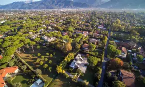 Vasta area residenziale con ville immerse nel verde, ideale per chi desidera comprare e vendere case in un contesto tranquillo con montagne sullo sfondo.