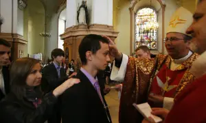 Bierzmowanie: młody mężczyzna otrzymuje błogosławieństwo od biskupa, a jego świadek kładzie mu rękę na ramieniu.