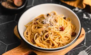 Ein Teller mit authentischer Spaghetti Carbonara, garniert mit Pecorino und schwarzem Pfeffer.