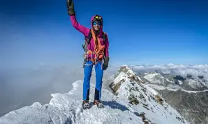 Erfolgreiche Bergsteigerin jubelt auf dem schneebedeckten Matterhorn Gipfel.