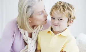 Una nonna bacia un bambino sorridente. Nonostante la tenerezza, i bambini non si baciano sempre, ma questo momento è speciale.