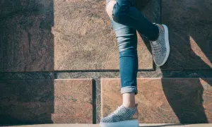 Nogawki jeansów podwinięte na kostkach, odsłaniające modne sneakersy. Idealny sposób, jak podwinąć spodnie na lato.