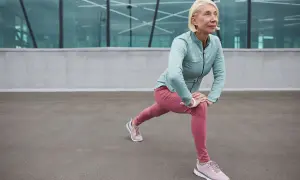 Donna bionda in abiti sportivi fa stretching, contrastando l'atonia muscolare con un affondo.