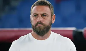 Close-up of a man with a beard and blue eyes wearing a white t-shirt.
