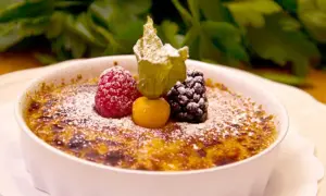 En krämig crema catalana toppad med bär och pudrat socker, en ljuvlig dessert.
