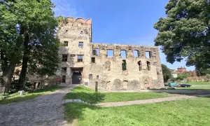 Kamienne mury i wieża zamku w Ząbkowicach Śląskich, otoczone zielenią, zapraszają do odkrywania historii.