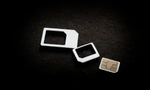 Trzy białe ramki na karty SIM i jedna karta SIM na czarnym tle.