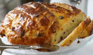 Ein goldbraun gebackenes Osterbrot mit Rosinen, glasiert und angeschnitten, bereit zum Genießen.