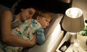 Mamma e figlio dormono abbracciati a letto, avvolti in una coperta con koala. Un momento di pace prima che i miei figli si sveglino.
