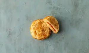 Två gyllene plättar, en hel och en delad, med en röd fyllning. Perfekta pannkakor för frukost eller fika.
