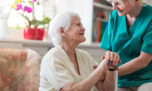 Une aide-soignante soutient une résidente souriante. Une maison de retraite moins cher offre un cadre de vie agréable et sécurisé.