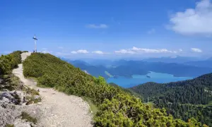 Gipfelkreuz nach einer Heimgarten Wanderung mit Blick auf einen türkisfarbenen See und Berge.