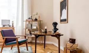 Stylowe wnętrza retro: fioletowy fotel, drewniany stolik z popiersiem i książkami, regał pełen literatury, gramofon i mapa na ścianie.
