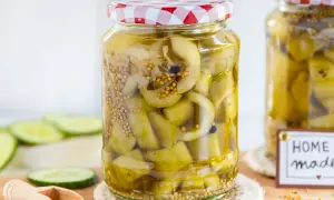Glas mit eingelegten Senfgurken, perfekt für ein Senfgurken Rezept. Frische Gurkenscheiben und Senfkörner sind sichtbar.