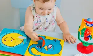 Dziecko bawi się kolorową książeczką sensoryczną z motywem słonia i słońca.