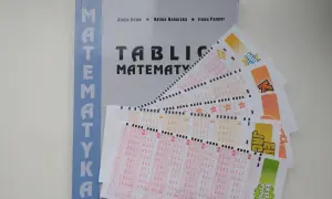 Matematyka w zdrapkach: jak obliczyć wartość oczekiwaną kuponu? Książka i kupony lotto na stole.
