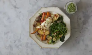 Ugnsrostade rotfrukter med fetaost, serverade med gröna blad och en grön topping.