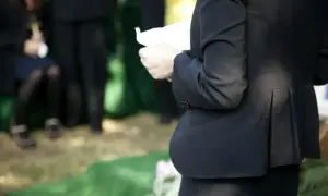 Smutne wspomnienie o zmarłej osobie. Kobieta w czerni trzyma kartkę, być może przemówienie pożegnalne.