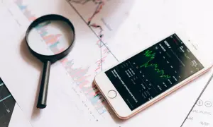 Analiza wykresów giełdowych i smartfon z danymi rynkowymi. To jakby przygotowanie do decyzji o leasing operacyjny.