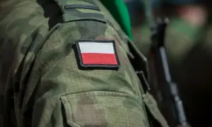Żołnierz w mundurze moro z polską flagą na ramieniu, gotowy do służby, symbolizuje dumę i poświęcenie, które towarzyszą emerytura wojskowa.