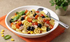 Un piatto invitante di pasta fredda tonno, con pomodorini, olive nere e mais. Perfetta per un pasto estivo.