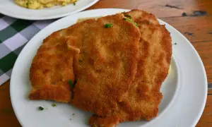 Zwei goldbraune Schnitzel auf einem Teller, garniert mit Schnittlauch. Ein Klassiker der Berliner Küche, der Appetit macht.