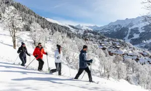 Quatre personnes font une randonnée en raquettes à Méribel en hiver, profitant du paysage enneigé et des montagnes.
