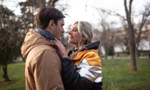 Para, która patrzy sobie w oczy w parku. Ona delikatnie dotyka jego policzka. Zastanawiasz się, czy napisać do faceta, który przestał się odzywać?