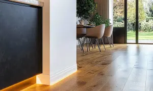 Nowoczesne wnętrze z drewnianą podłogą i oświetleniem LED. Eleganckie rozwiązanie co zamiast listew przypodłogowych, tworzy subtelny blask.
