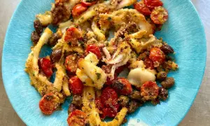 Deliziosi calamari gratinati al forno, croccanti e saporiti, con pomodorini e olive, serviti su un piatto blu.