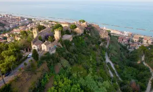 Borgo medievale su una collina affacciata sul mare Adriatico, con il lungomare di Cupra Marittima in lontananza.