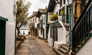 Calle empedrada con casas blancas y balcones de madera, ideal para pasear y descubrir qué ver en Algorta.