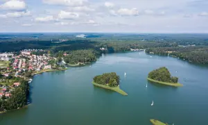 Malownicze jeziora w Polsce na wakacje. Widok z lotu ptaka na miasteczko nad wodą, wyspy porośnięte drzewami i żaglówki.