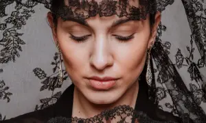 Mujer con peinados de mantilla, luciendo pendientes largos y un abanico de encaje.