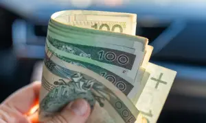 Dłoń trzyma banknoty 100 zł. Kiedy wypłata 13 i 14 emerytura 2026?