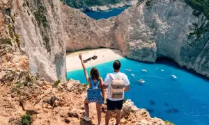 Couple admirant la baie de Navagio, une des plus belles plages des top 5 des îles grecques. L'eau turquoise et les falaises blanches sont spectaculaires.