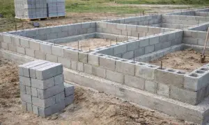 Fundament domu wznoszony z bloczków zalewowych. Widać ułożone ściany fundamentowe i zapas materiału.