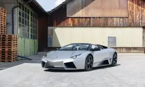 Srebrny, otwarty Lamborghini Reventon stoi przed rustykalnym budynkiem.