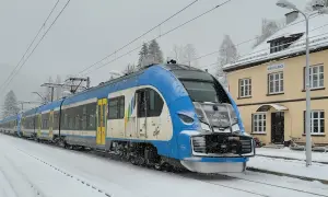 Niebiesko-biały pociąg Kolei Śląskich na stacji Wisła Głębce, od kiedy pociągiem do Wisły, w śnieżny dzień.