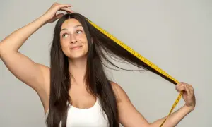 Mujer se mide el pelo con cinta métrica, curiosa por saber cuanto tarda en crecer el pelo.