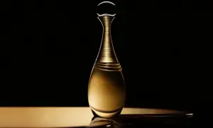 Złota butelka perfum Dior J'adore Infinissime na czarnym tle, emanująca luksusem i elegancją.