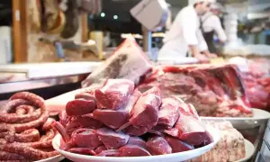 Carnes grasas y magras en un puesto de carnicería. Salchichas en espiral y chuletas de cordero apiladas en platos.
