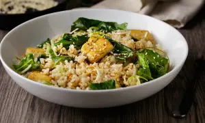 Deliciosa ensalada de arroz con trozos de tofu dorado, espinacas frescas y semillas de sésamo. Un plato nutritivo y lleno de sabor.