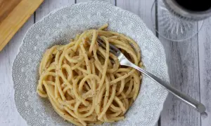 Porcja pysznego cacio e pepe z widelcem w talerzu, gotowa do zjedzenia.