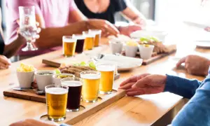 Un gruppo di persone partecipa a un corso degustazione birra, assaggiando diverse varietà accompagnate da stuzzichini.