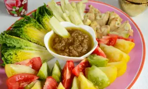 Assiette colorée de légumes frais (laitue, tomates variées, céleri) autour d'un bol de bagna cauda.