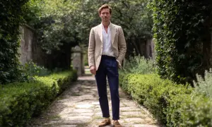Ein Mann in einem beigen Sakko, weißem Hemd und dunkelblauen Hosen. Perfekt, wenn man sich fragt, was zieht man zur Taufe an.