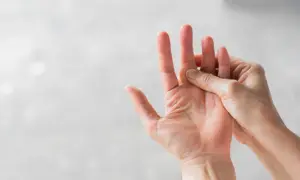 Hand massiert einen schmerzenden Finger, der auf eine Prellung hindeutet.
