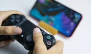 Ręce trzymające kontroler DualSense, gotowe do gry na telefonie. Dowiedz się, jak podłączyć pada PS5 do telefonu, by cieszyć się grami mobilnymi na nowym poziomie.